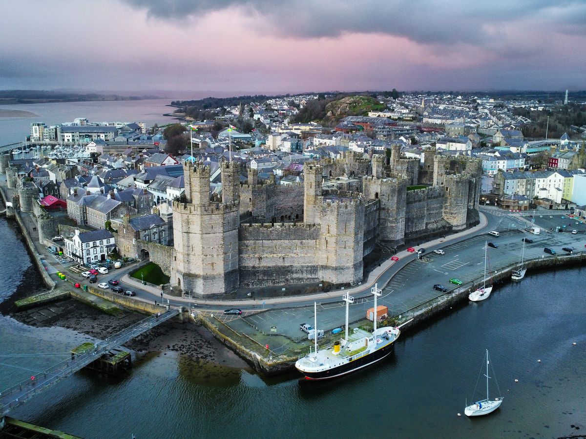 Aerial view of a coastal castle and harbour town at dusk