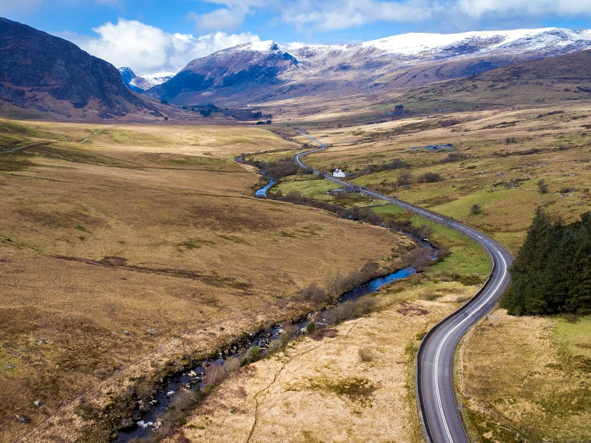 Aerial view of a winding road through a snow-capped mountain valley